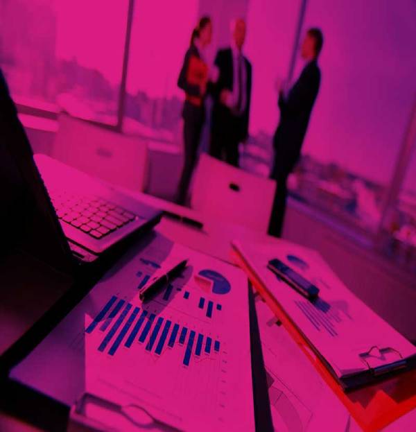 desk with a laptop and covered with paperwork